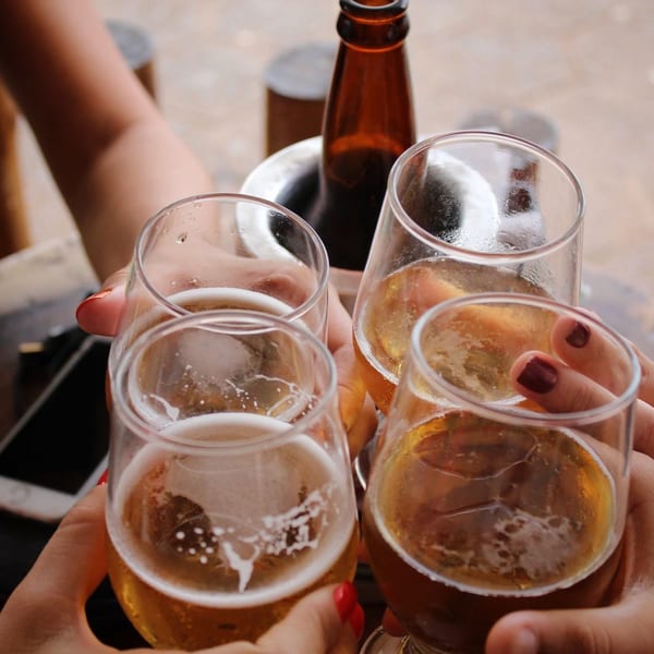 Four people clinking glasses of beer, with a beer bottle in an ice bucket in the background.